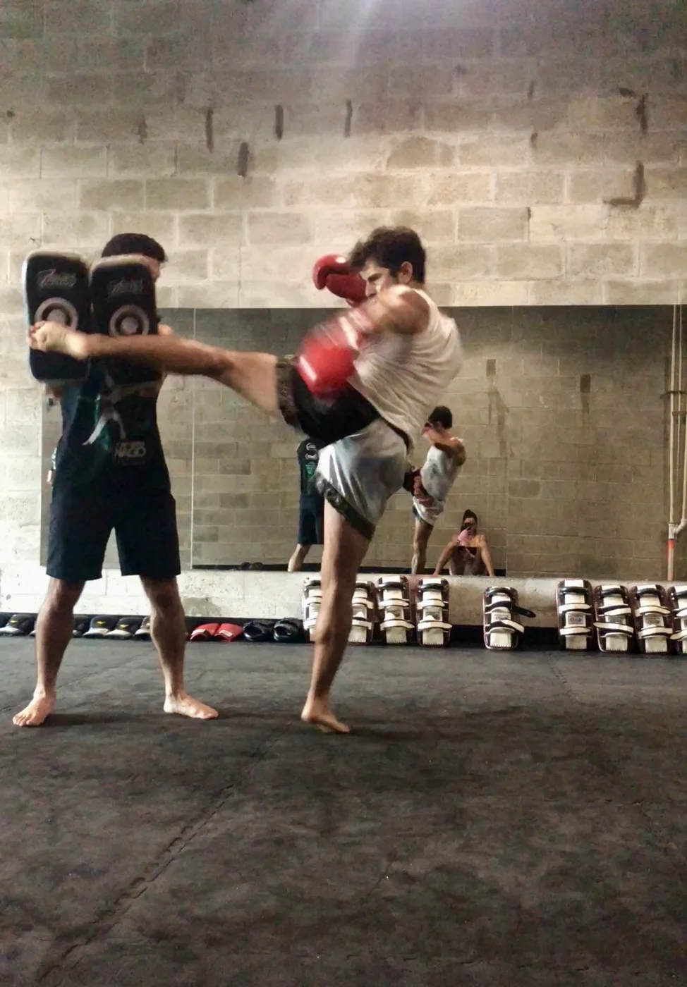 Coach Gui throwing a Muay Thai kick on pads